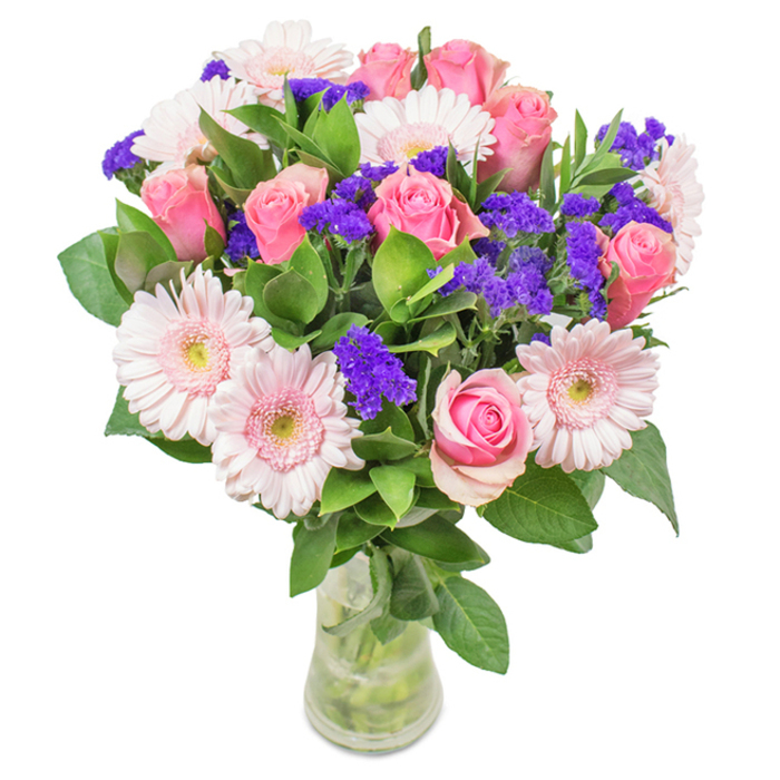 This stunning Stanmore bouquet is presented in a crystal-clear glass vase, set against a pristine background that highlights every detail. Seven to nine roses in coordinated shades of pink are at the heart of the design-their spiraled petals captured at stages from tight bud to open bloom, each reflecting expertise honed at Flower Delivery Stanmore. Five to seven pale pink gerbera daisies surround them, their large, round faces and lighter central discs providing soft contrast and appealing symmetry. Throughout, clusters of bright purple statice add textural contrast and deeper hue, bringing a touch of vibrancy reminiscent of Stanmore's lush gardens and green spaces. Generous sprays of rich, fresh foliage enhance the arrangement's vitality, their deep green tones and subtle earthy fragrance referencing the natural abundance found in Stanmore countryside. The visible stems in the vase promise lasting freshness, echoing the quality of our local flower deliveries. This bouquet, ideal for birthdays, anniversaries, Mother's Day, or brightening a welcoming home near Stanmore Park, is an expression of joy and caring, artfully crafted for heartfelt occasions.